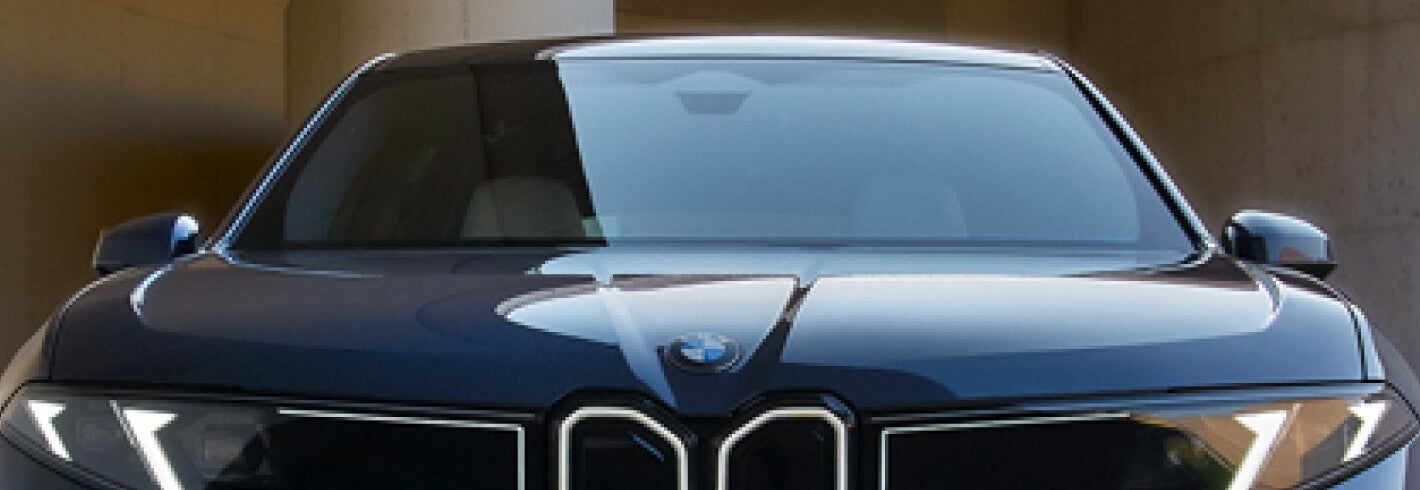 Cut off close-up front view of a BMW with the windshield prominently featured.