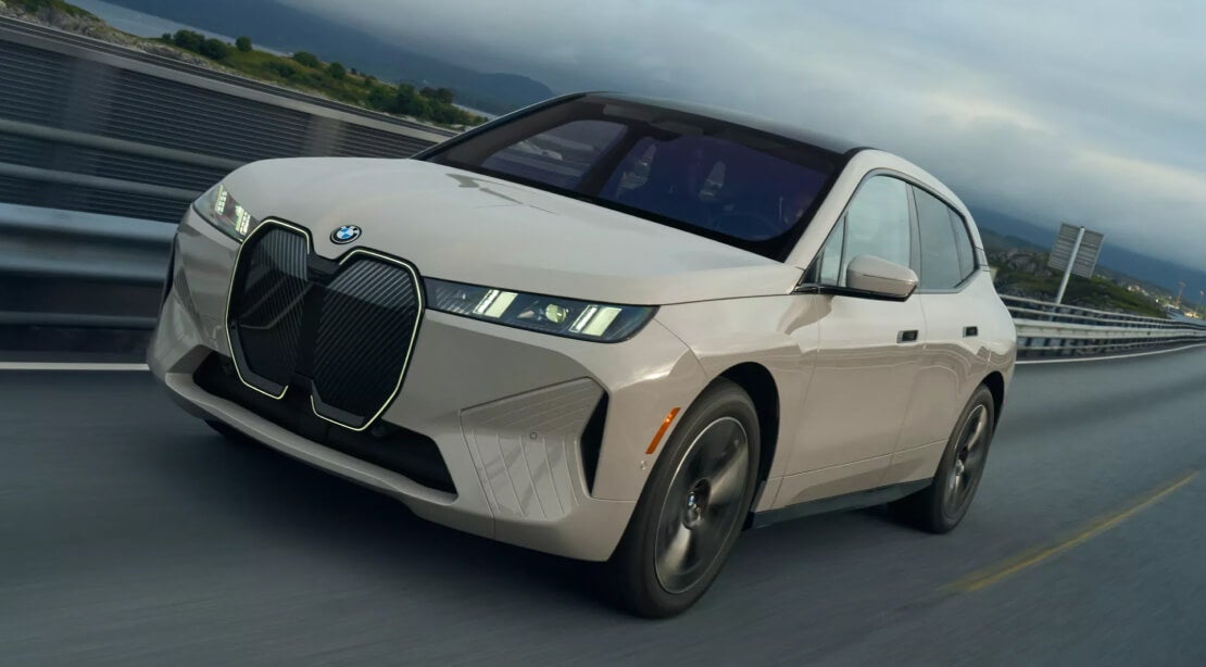 A front view of a cream BMW iX driving down a highway