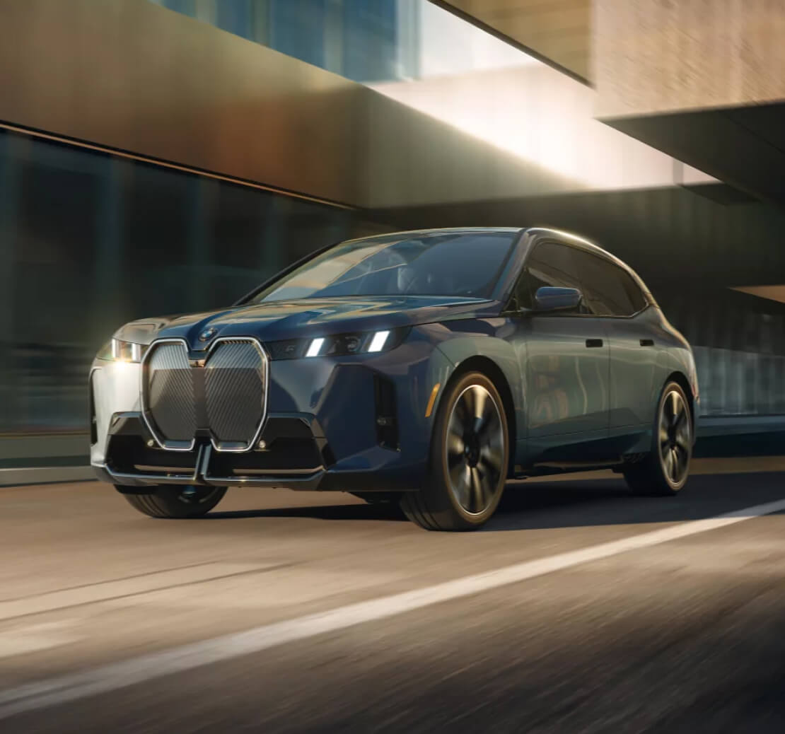 A front 3/4 view of a blue BMW iX as it drives down a city street